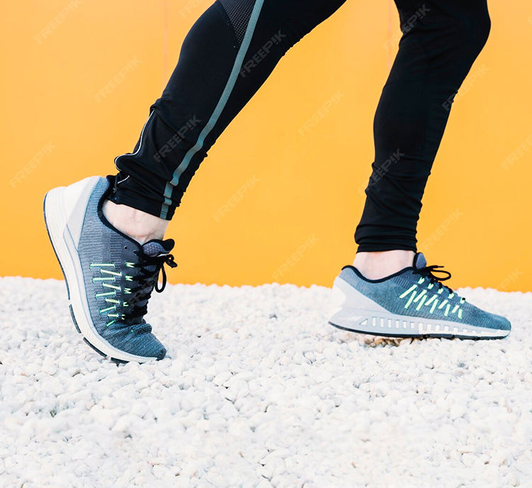 Person wearing blue running shoes with white soles on a textured surface against an orange background